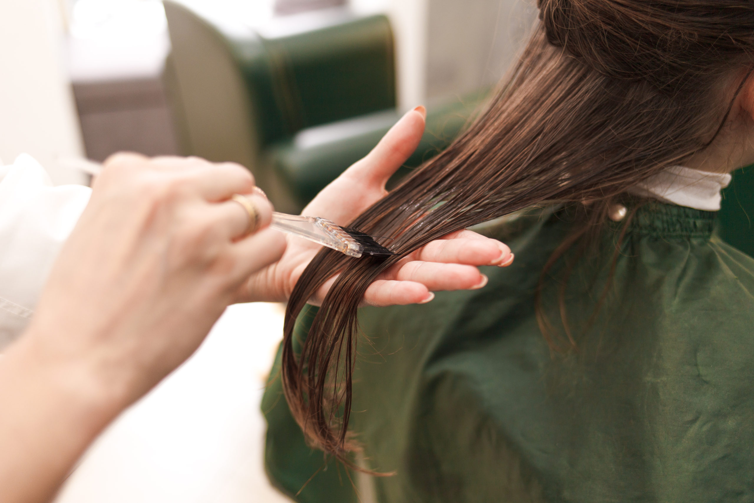 Hairdresser applies a hair mask to the woman in the beauty salon