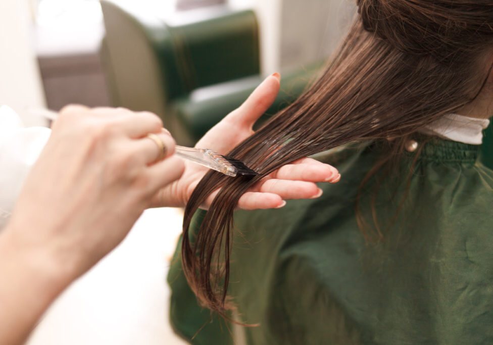 Hairdresser applies a hair mask to the woman in the beauty salon